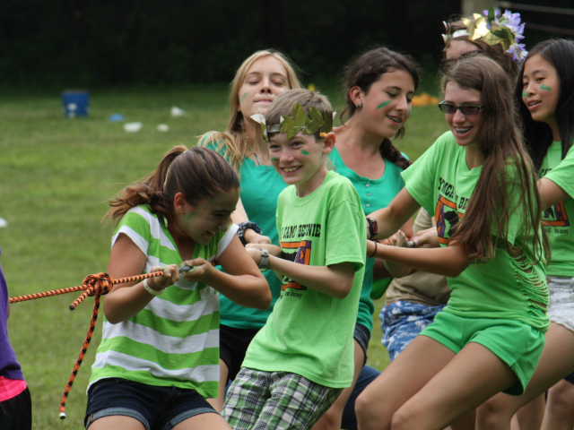 A group of kids in green shirts playing tug of war.